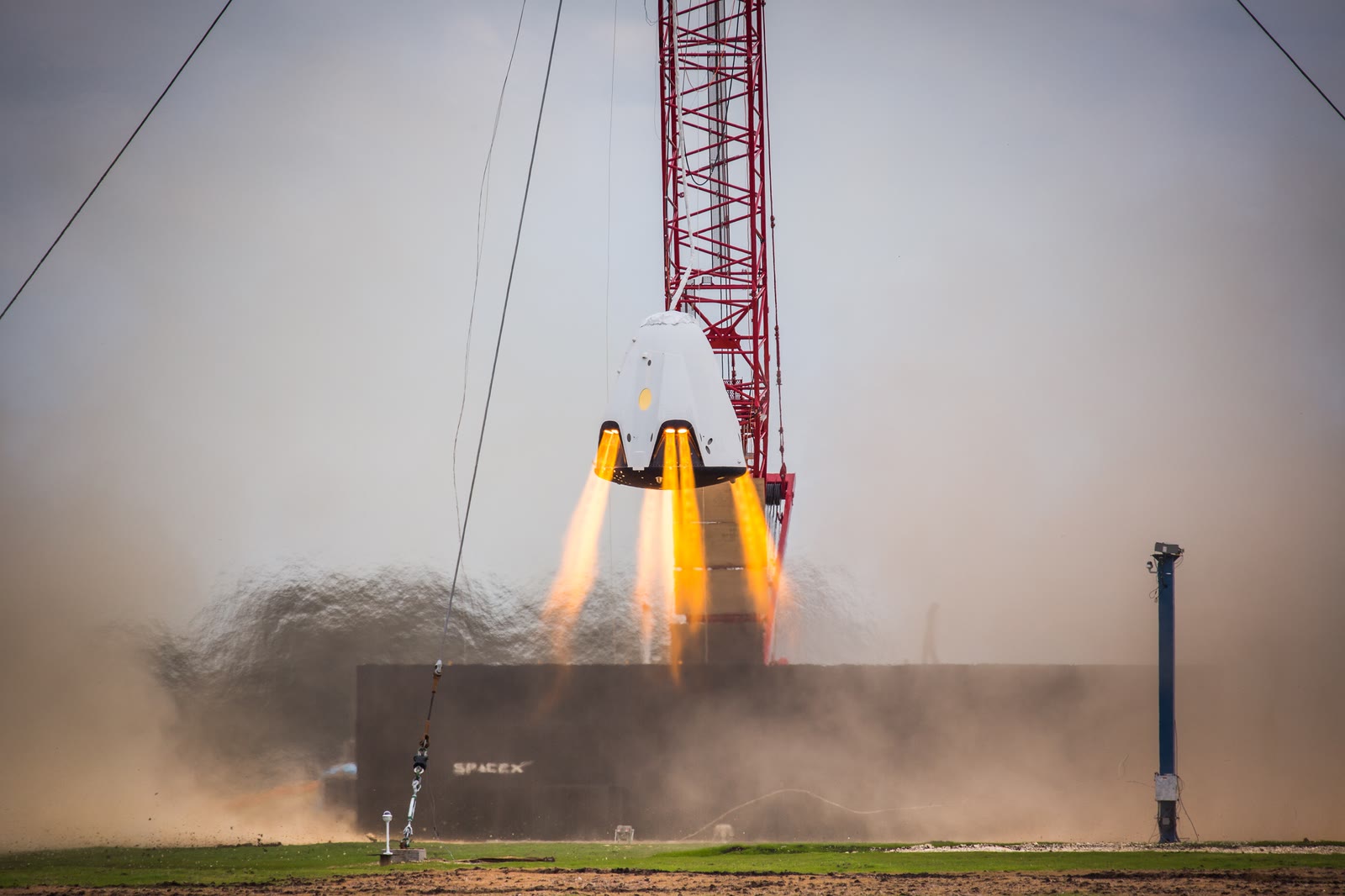 A Dragon 2 capsule hovering on its SuperDraco thrusters during a tethered test