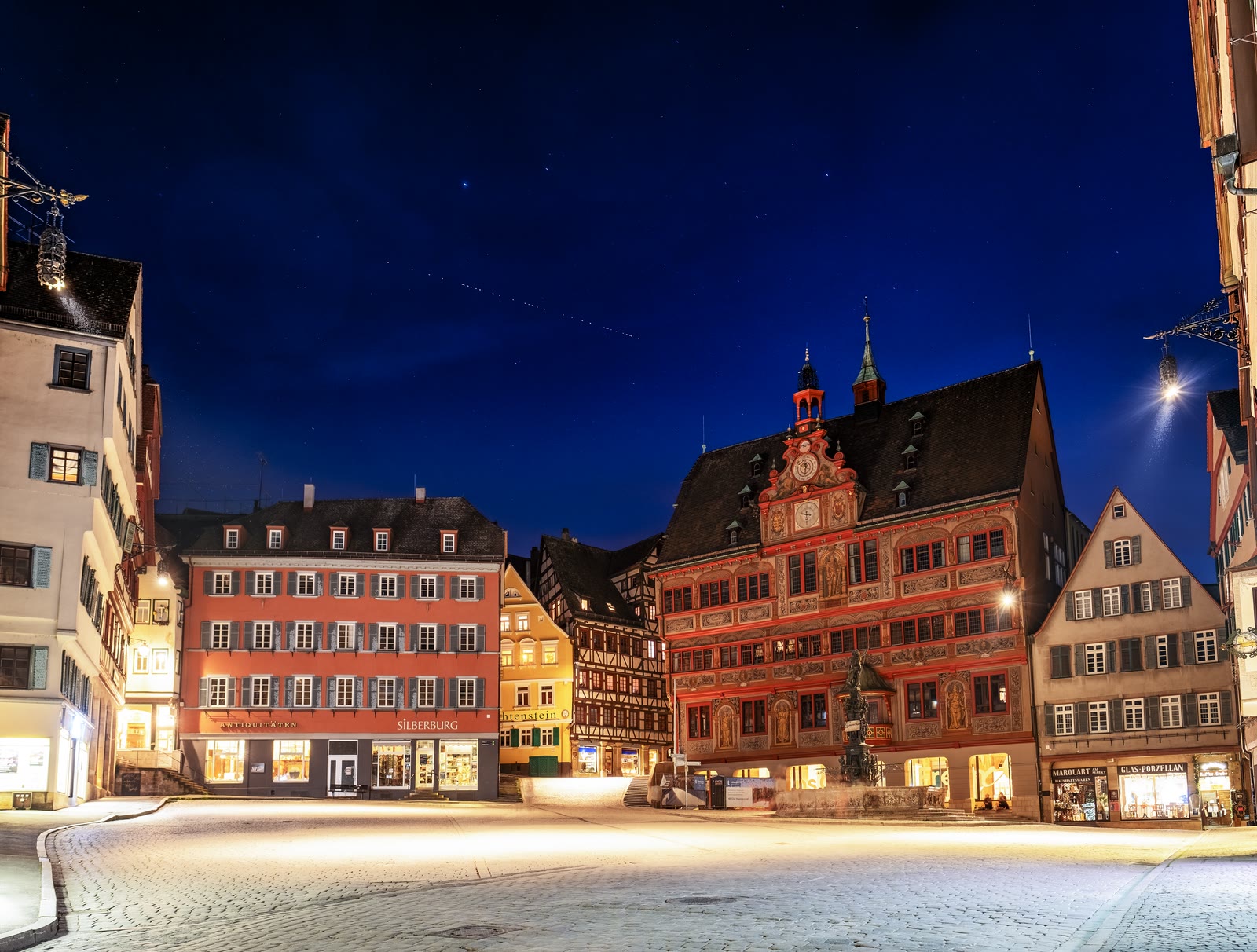 A line of newly launched Starlink satellites crossing the night sky above a town hall