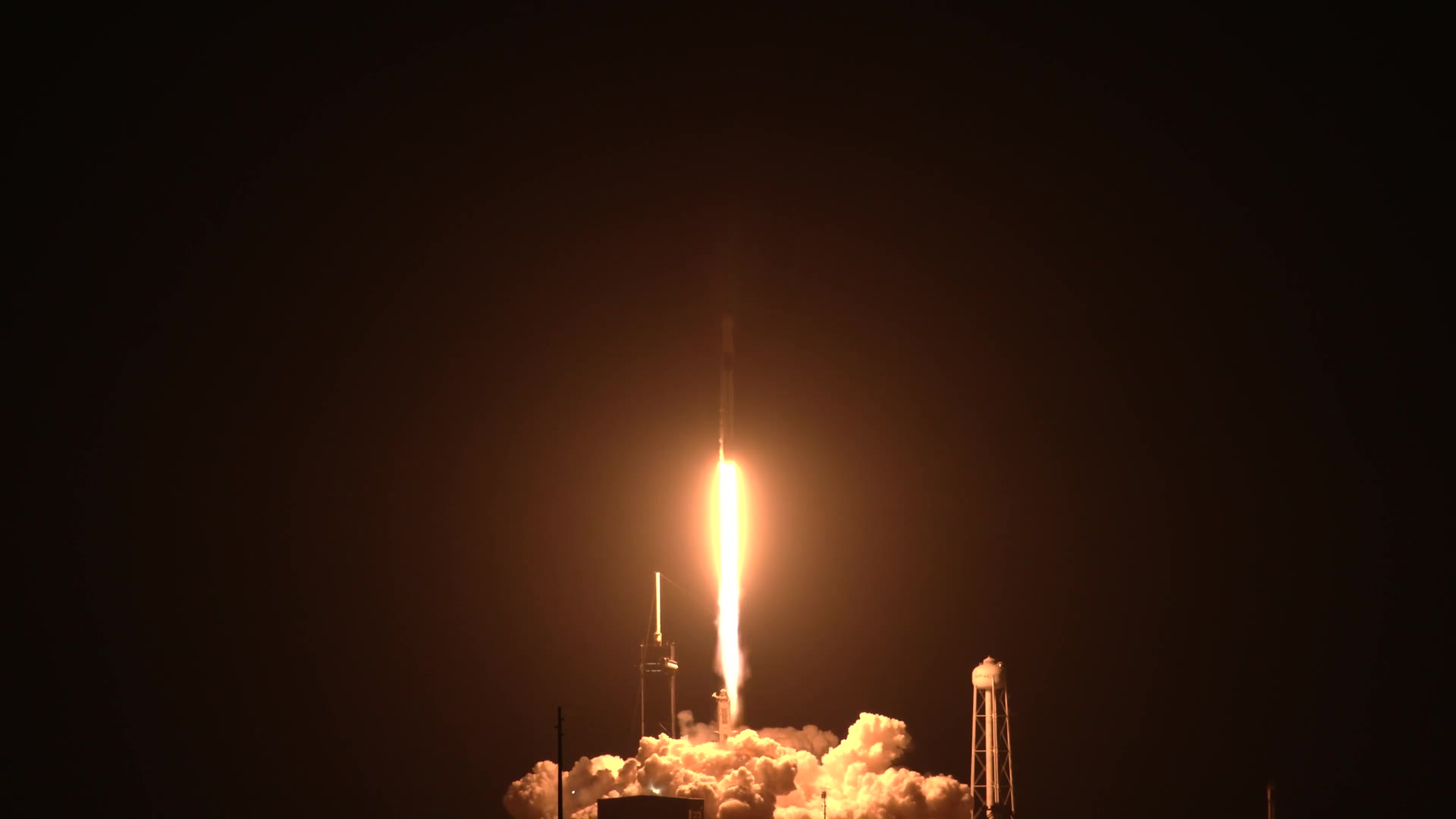 A Falcon 9 carrying Crew Dragon lifting off at night, its exhaust lighting the pad, November 15 2020