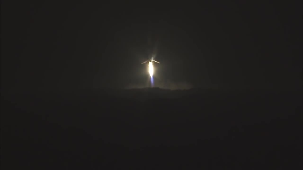 A bright point of light descends through the night and flares as the first Falcon 9 booster lands at Landing Zone 1, December 21 2015