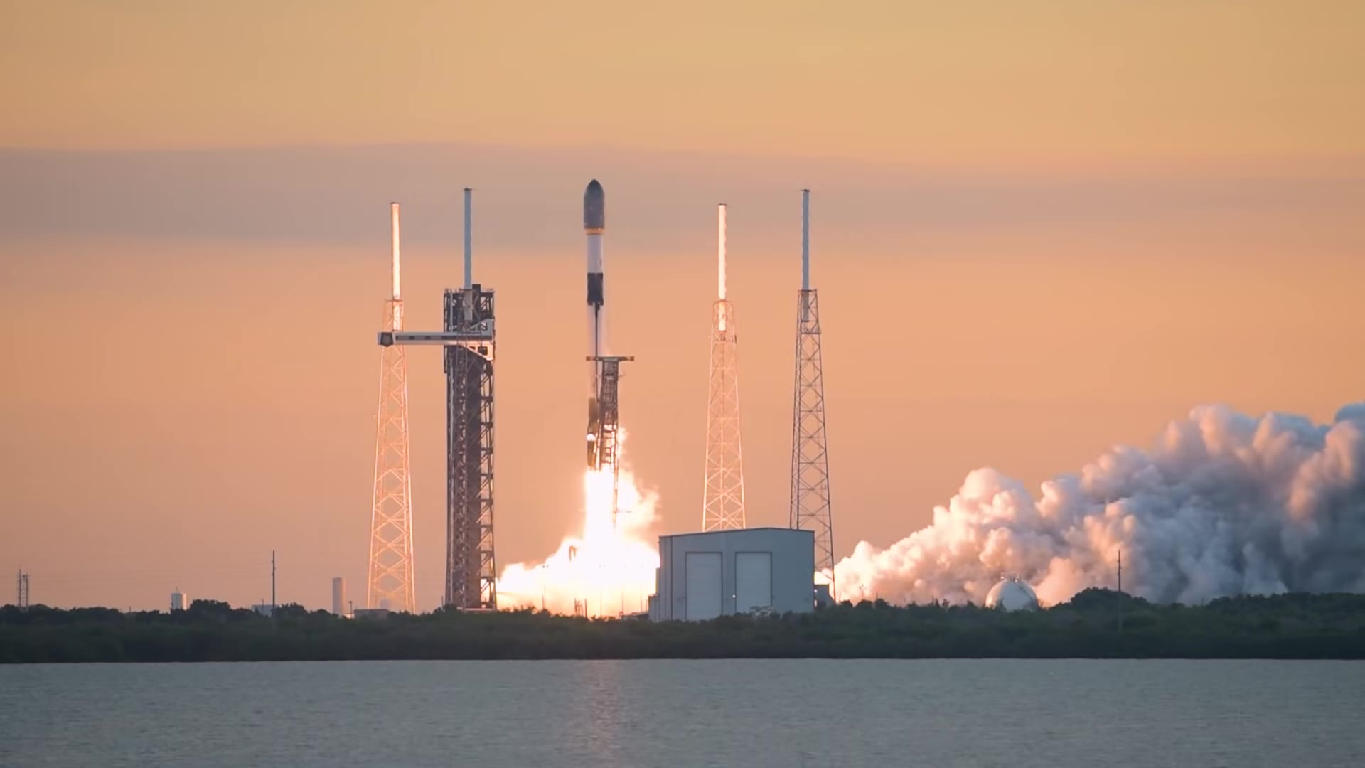 A Falcon 9 lifting off from Space Launch Complex 40 against a peach sunset sky on a Starlink mission